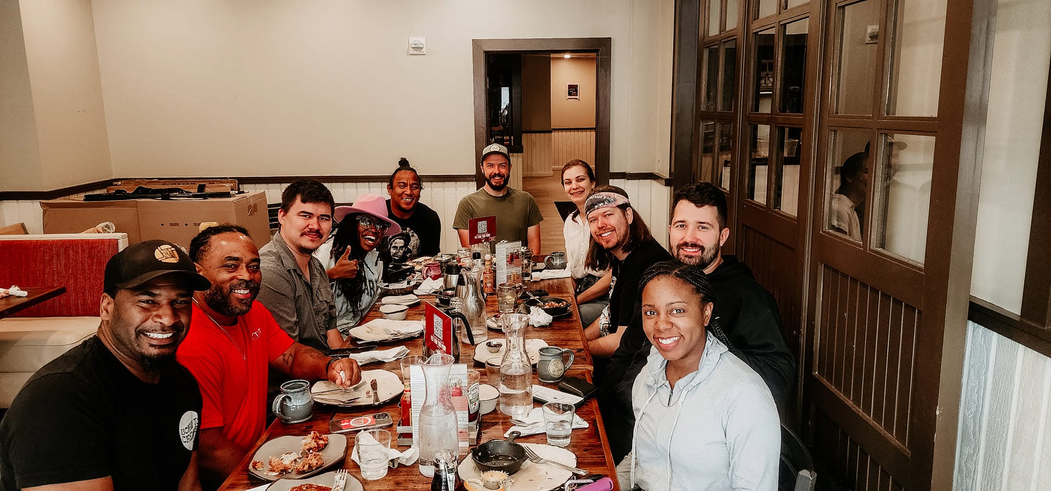 Atlanta Church Creatives members smiling together around a long table at a Monday Meetup