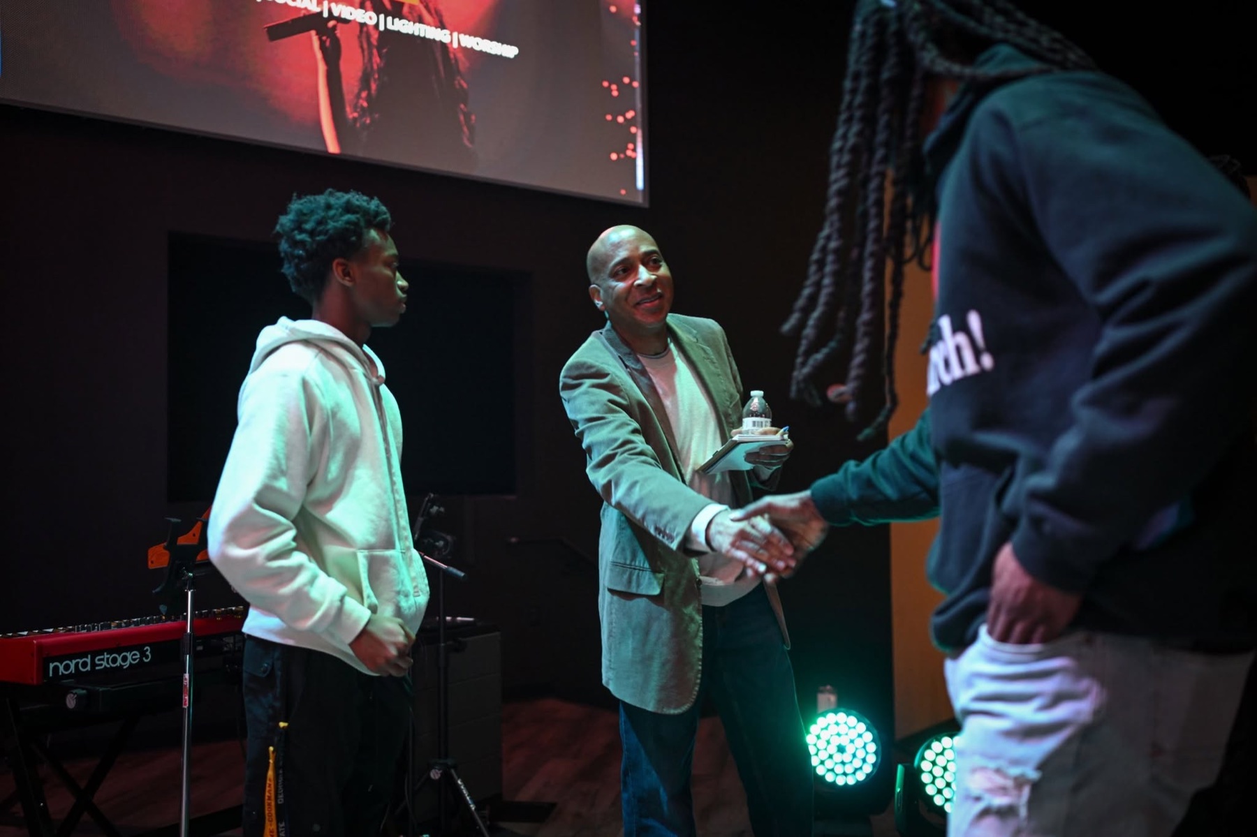 Conference attendees connecting with a presenter near the stage
